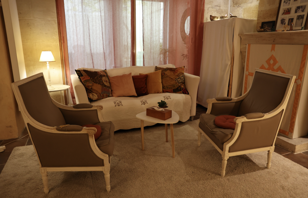 Salon chaleureux avec deux fauteuils, un canapé et une table basse dans un cabinet de thérapie