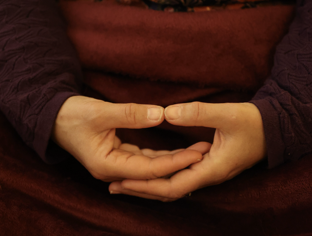 Mains posées en mudra de relaxation, doigts joints dans une posture méditative